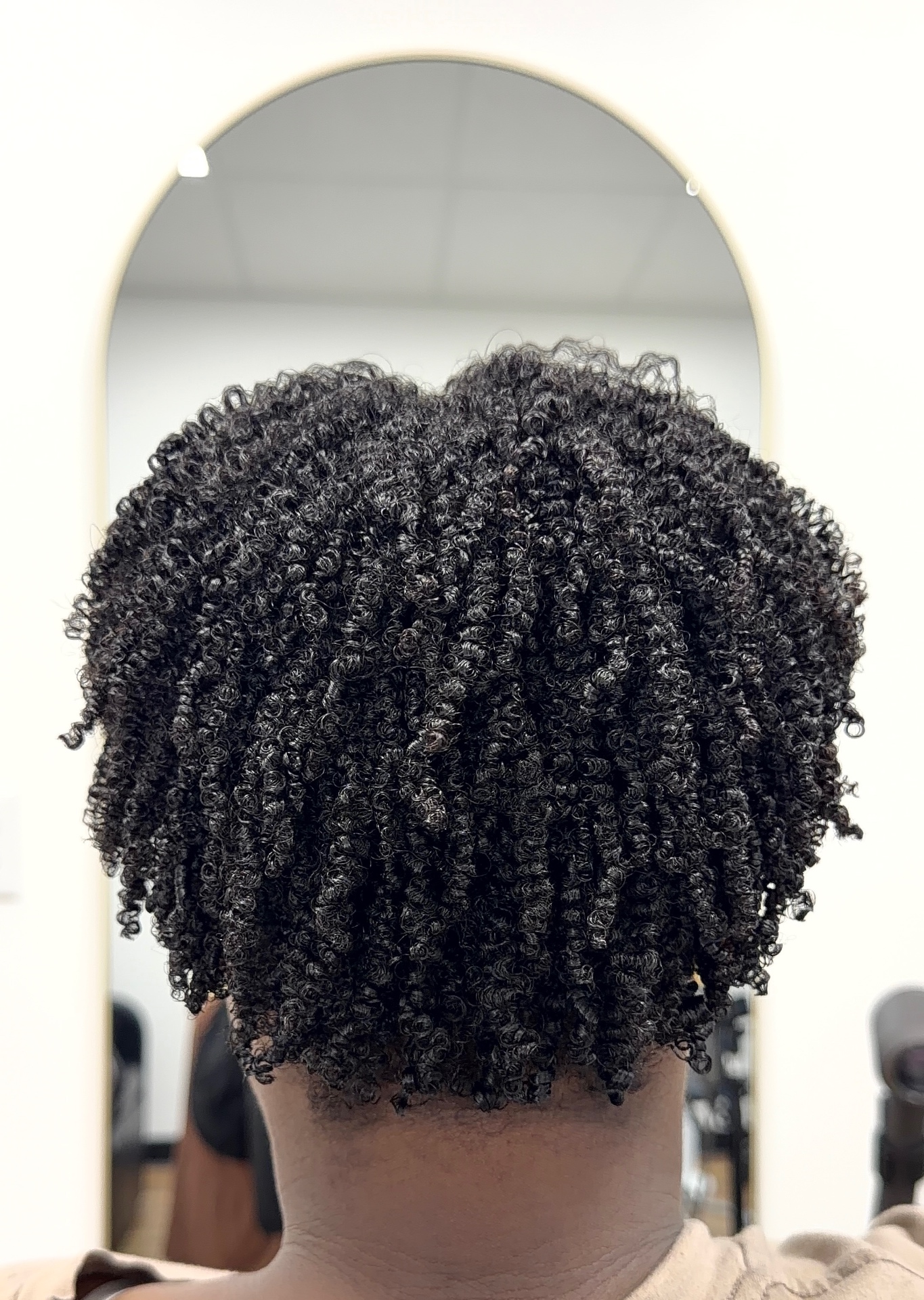 Client with tightly coiled natural hair shaped into a rounded silhouette